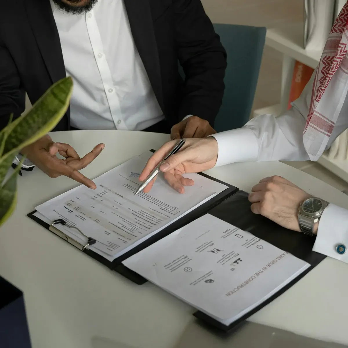 Two professionals reviewing contract documents at a table during a business meeting