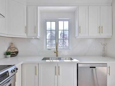 Bright white kitchen with gold tapware, white cabinetry, and stainless steel appliances