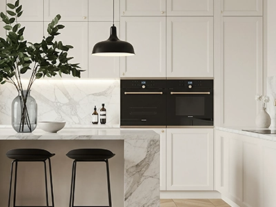 Modern white kitchen with black pendant light, marble island, and integrated ovens