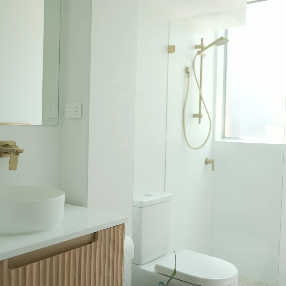 Modern white bathroom with timber vanity and brass fixtures