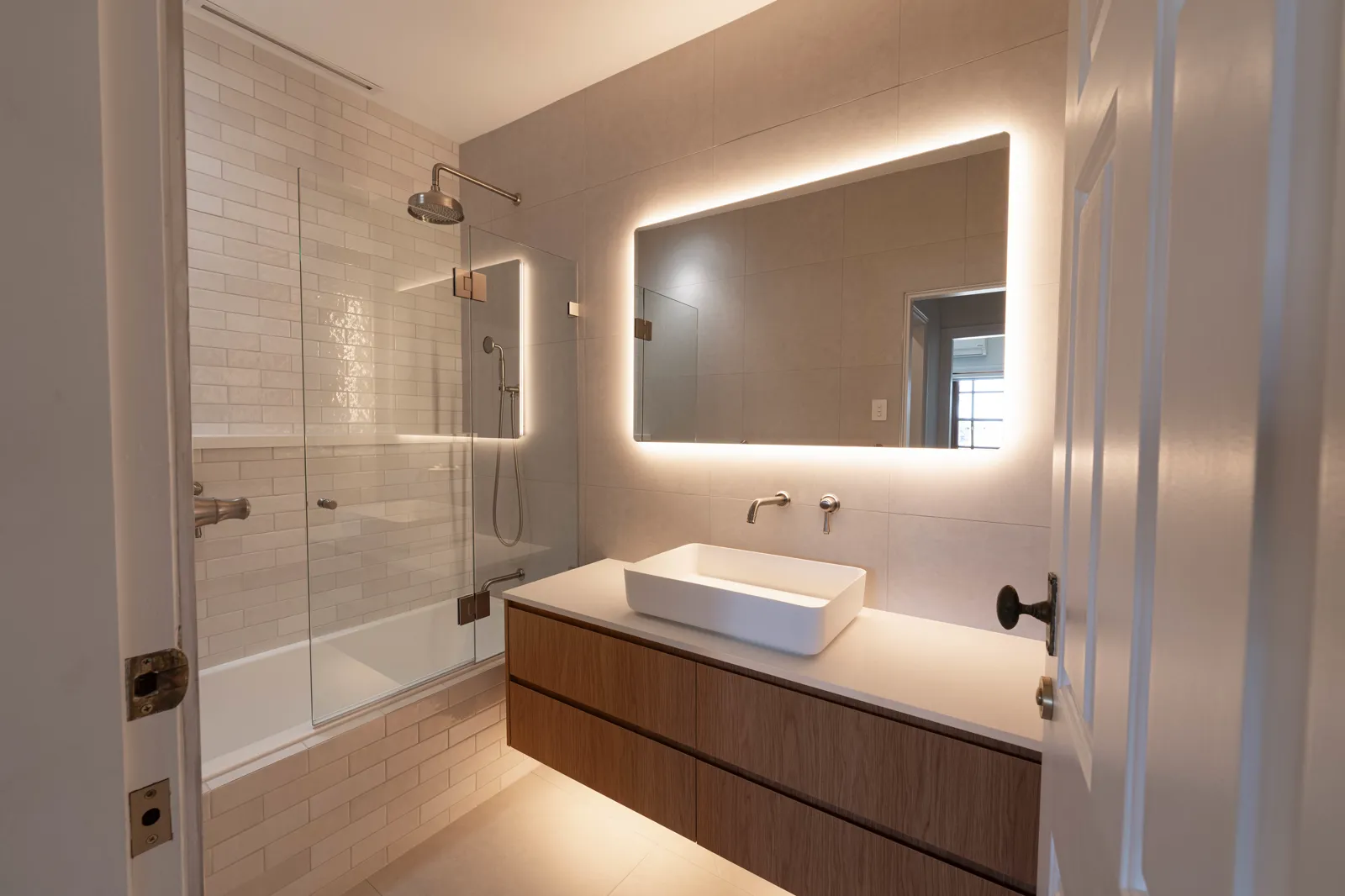 Main bathroom with floating timber vanity, vessel basin, LED backlit mirror and frameless bath screen