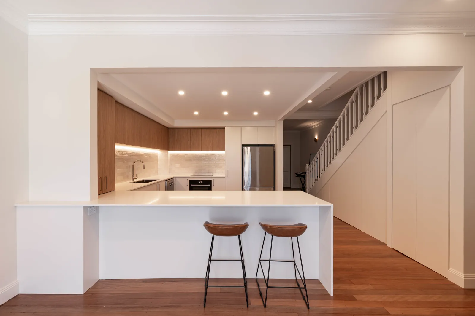 Open plan kitchen and living area with island bench, bar stools and walk-through pantry