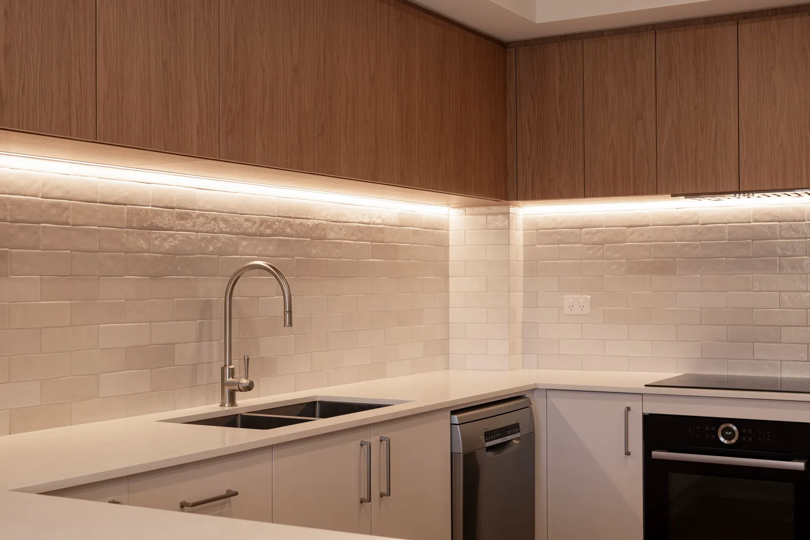 Kitchen splashback and under-cabinet strip lighting with brushed nickel tapware