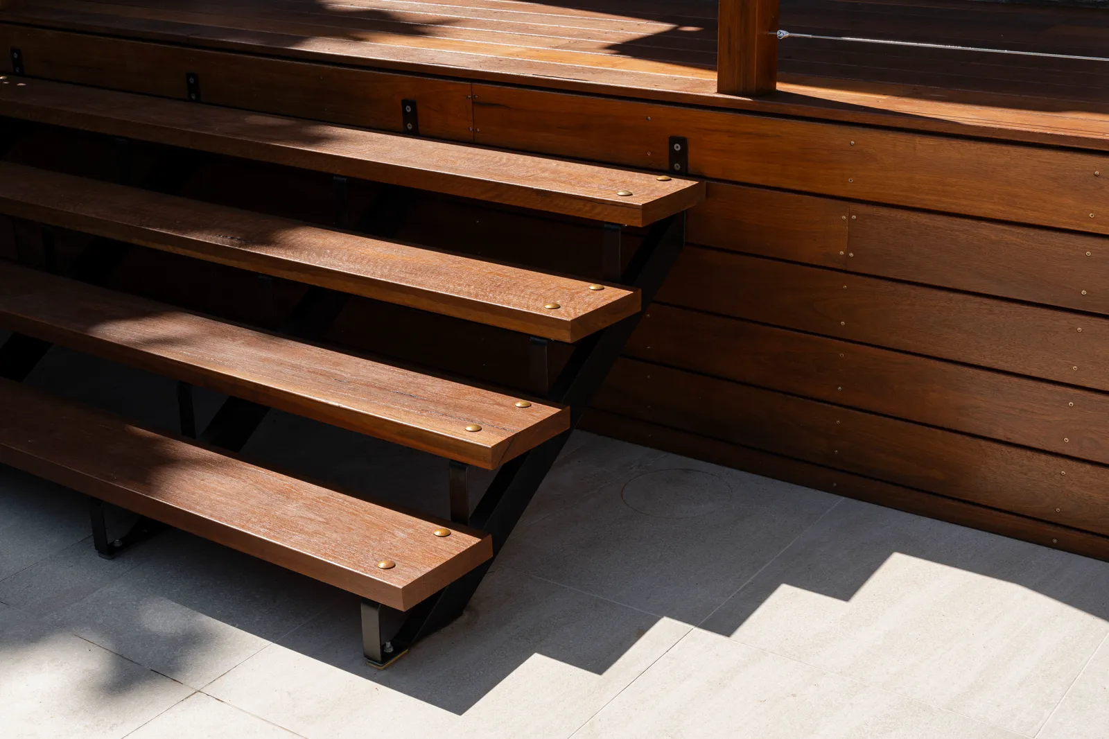 Spotted gum open riser staircase with steel stringers on travertine pavers