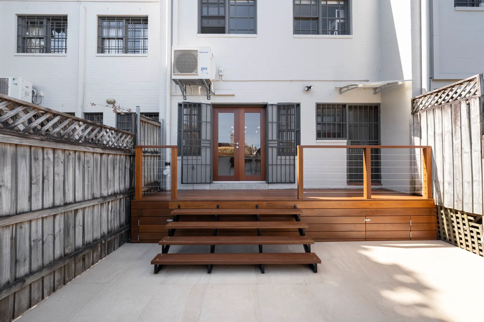 New outdoor area with spotted gum deck, steel staircase and travertine pavers