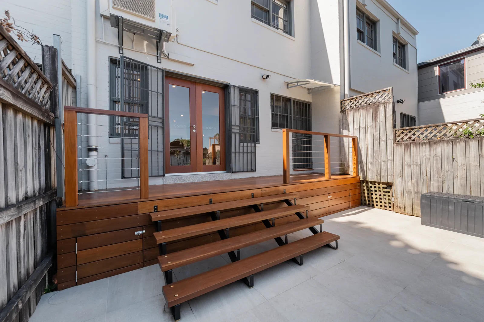 New spotted gum deck with open riser staircase and travertine pavers