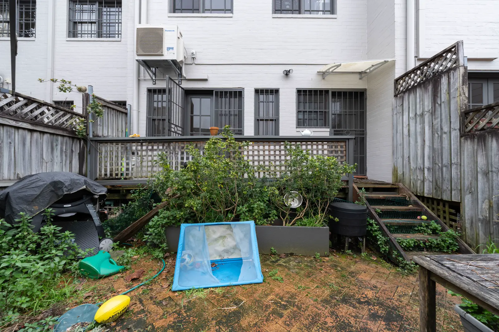 Original backyard before renovation with old deck and overgrown garden