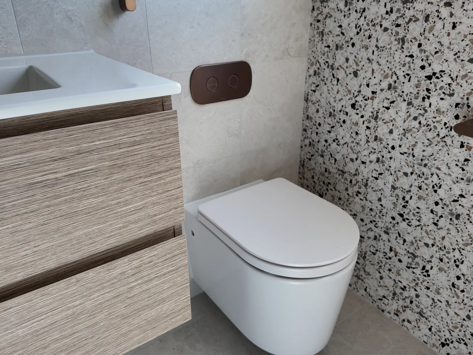 Back-to-wall toilet suite with a concealed in-wall cistern and brushed bronze flush plate