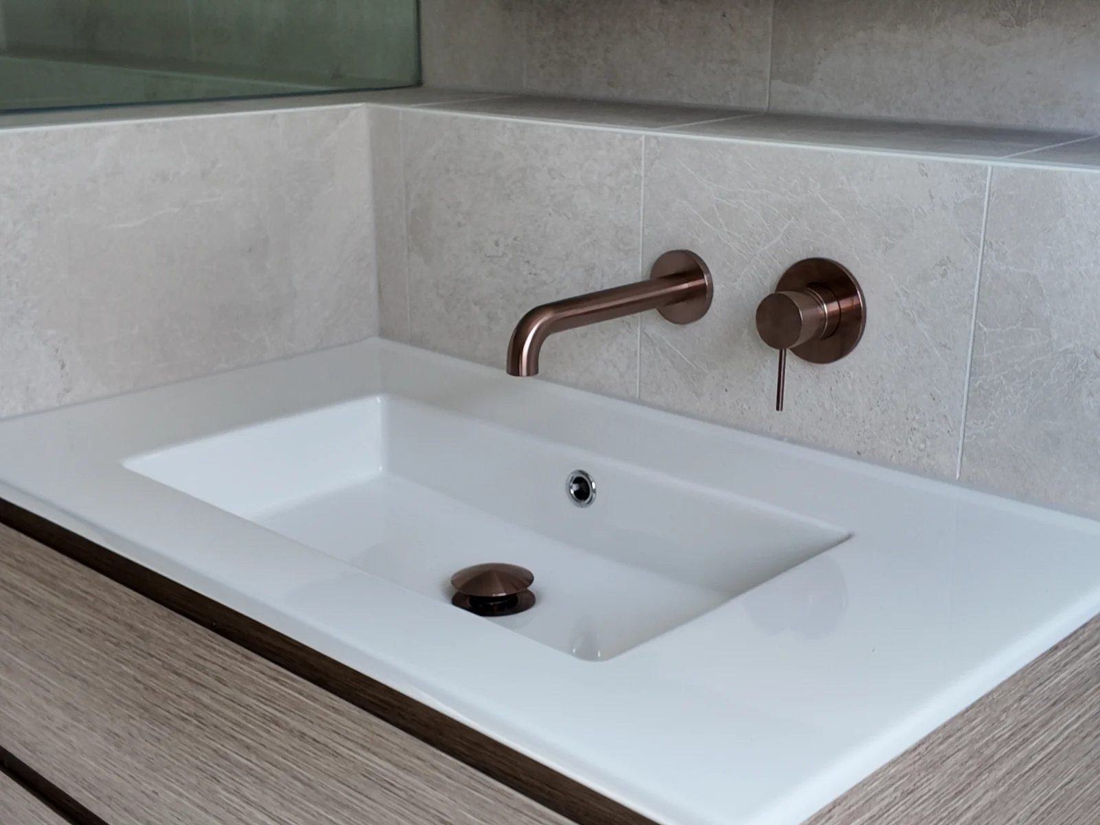 Wall-hung vanity with ceramic top and brushed bronze wall mixer in the renovated Coogee bathroom