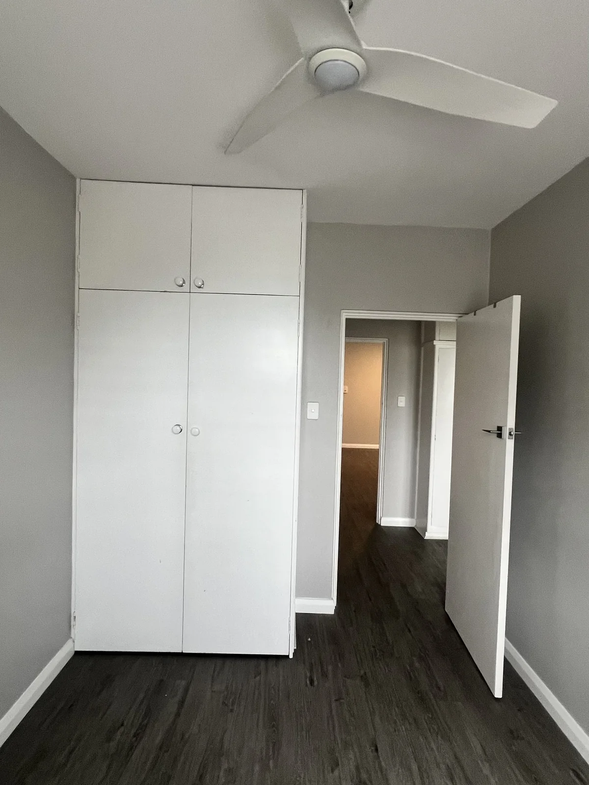 The kids bedroom before renovation, with an original painted built-in wardrobe and dark vinyl flooring