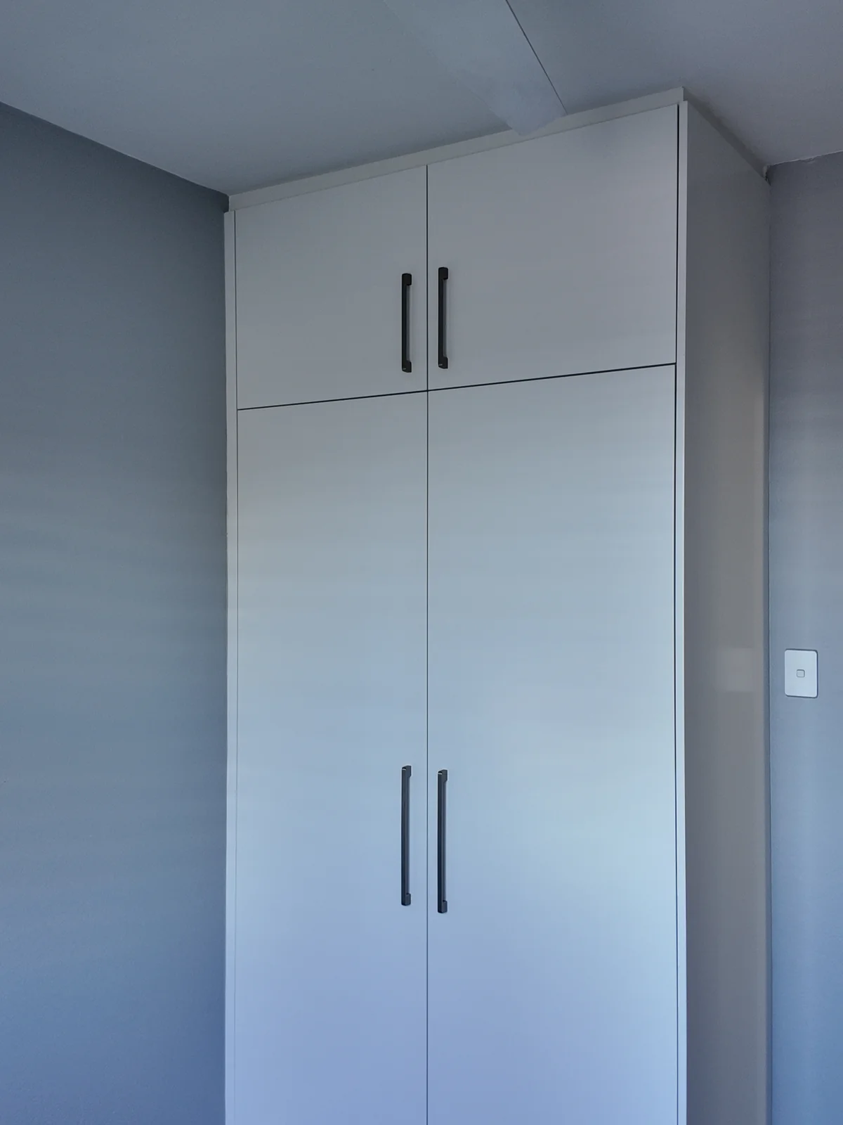 The kids bedroom after renovation, with new full-height built-in wardrobe joinery and matt black handles
