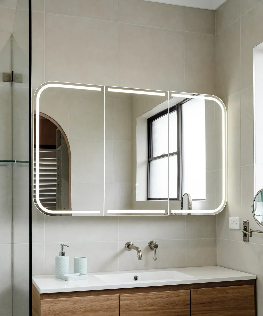 Ensuite timber vanity with LED backlit mirror cabinet, wall-mounted brushed nickel tapware and arched niche