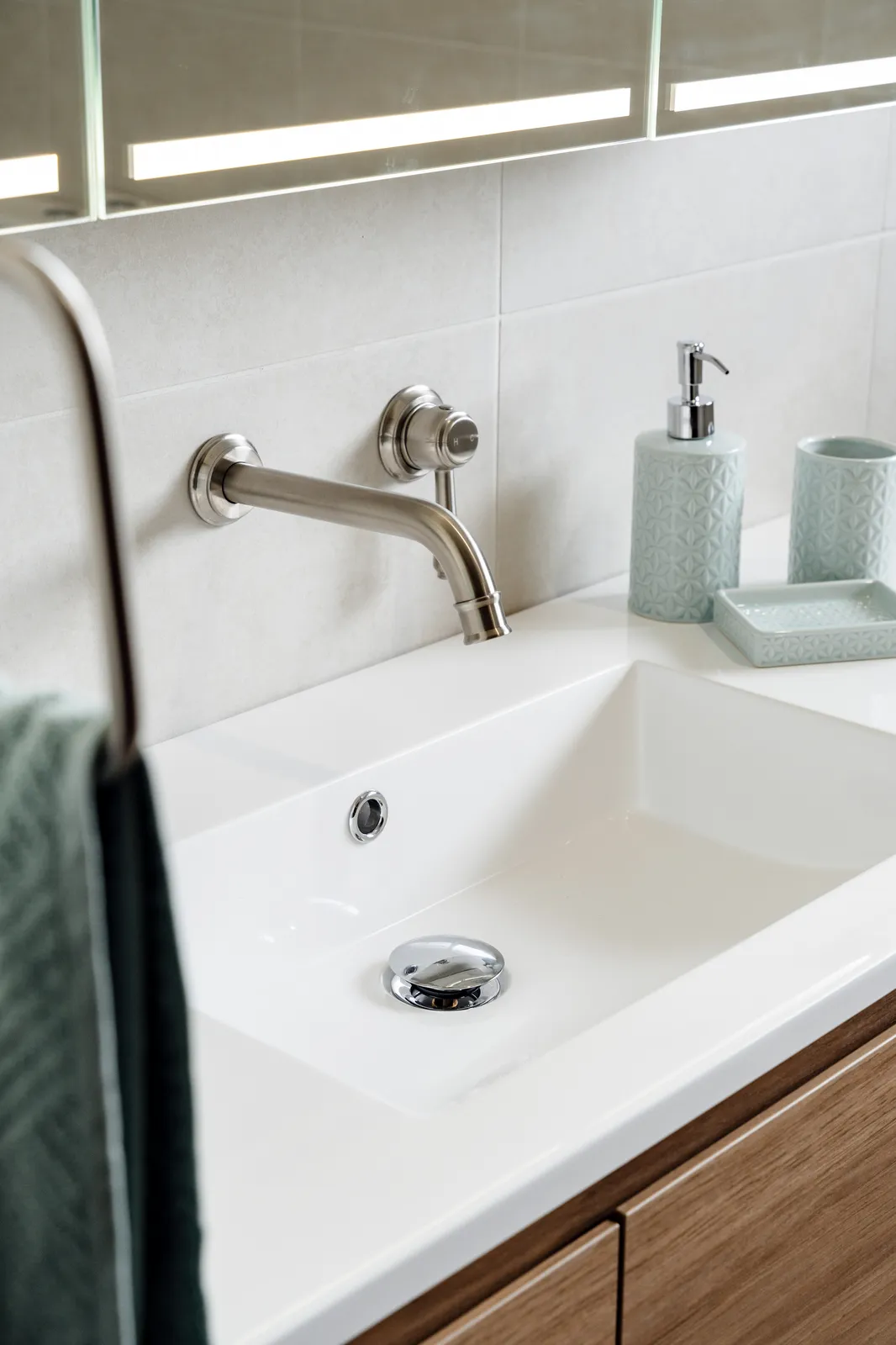 Wall-mounted Kingsley brushed nickel basin spout on white stone benchtop with undermount basin