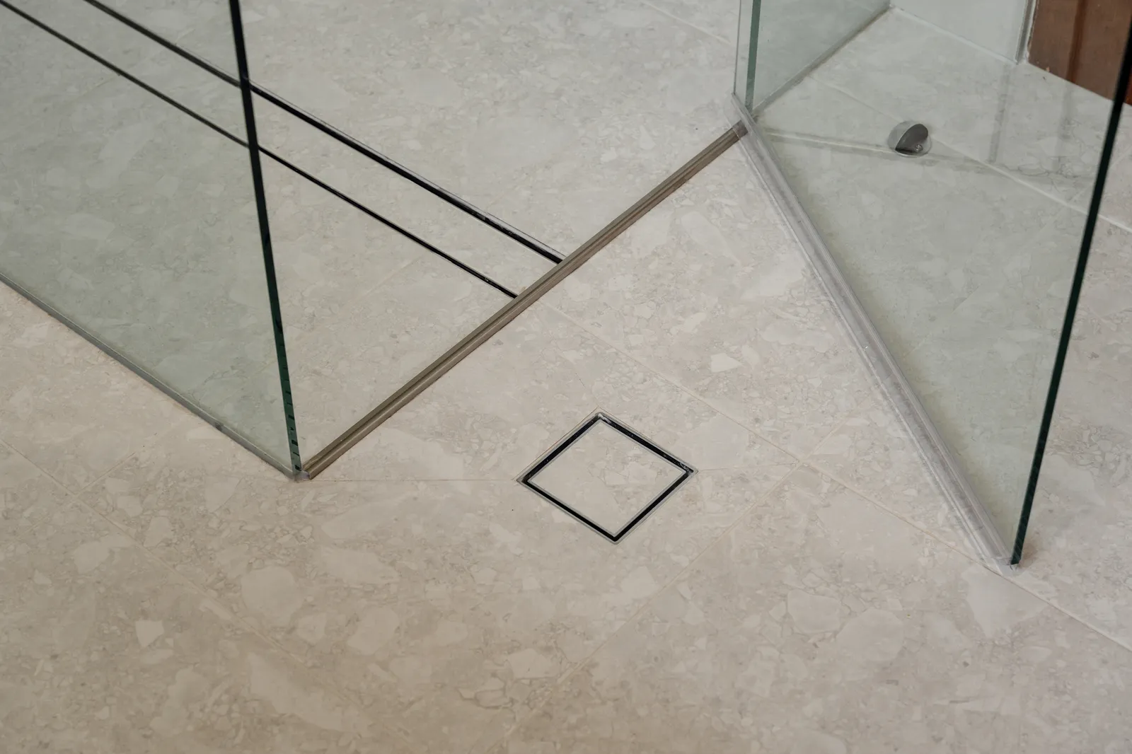 Tile-insert floor waste with frameless glass panels on stone-look porcelain tiles