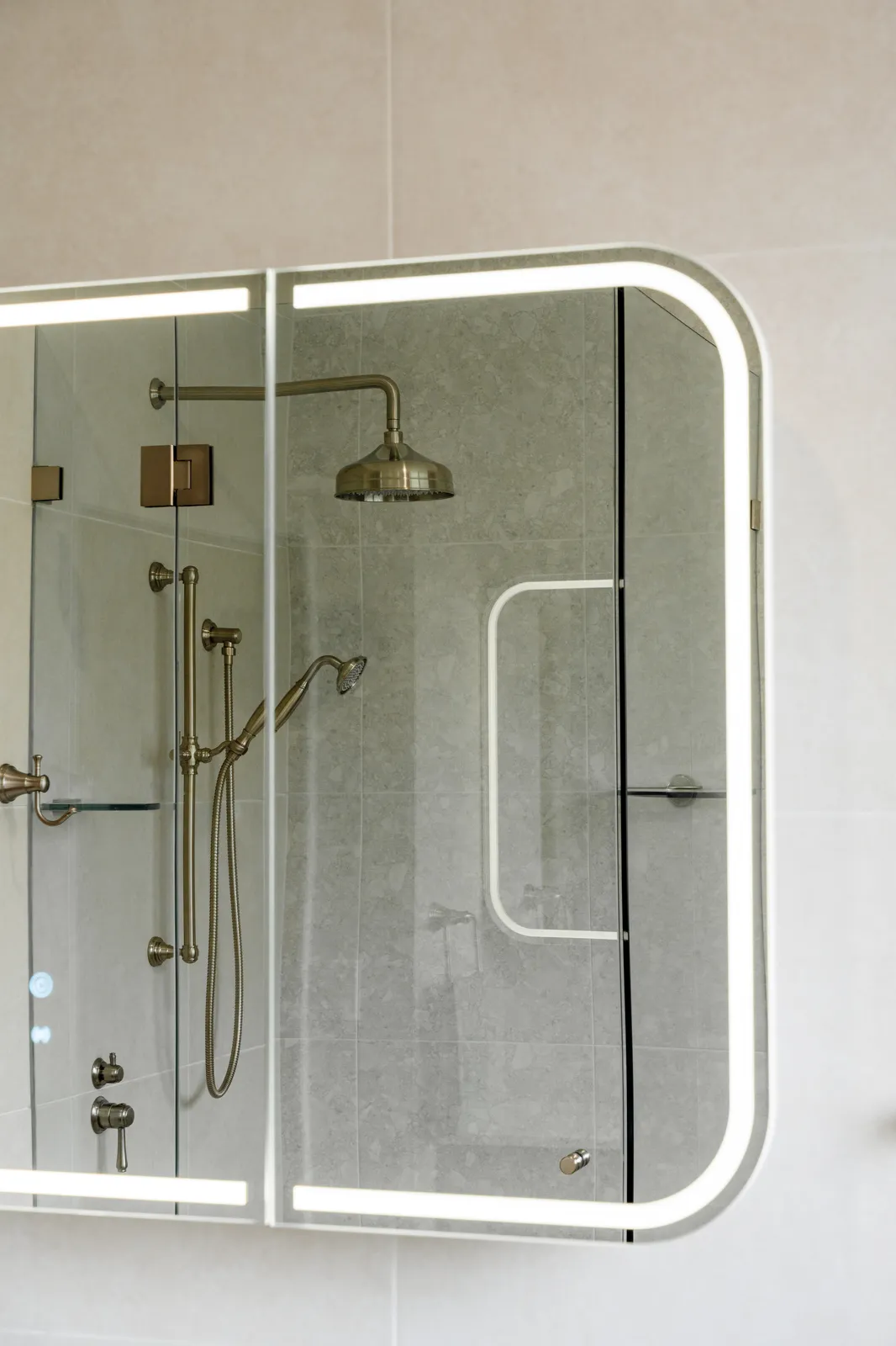 LED backlit mirror cabinet reflecting frameless glass shower screen and brushed nickel shower tapware