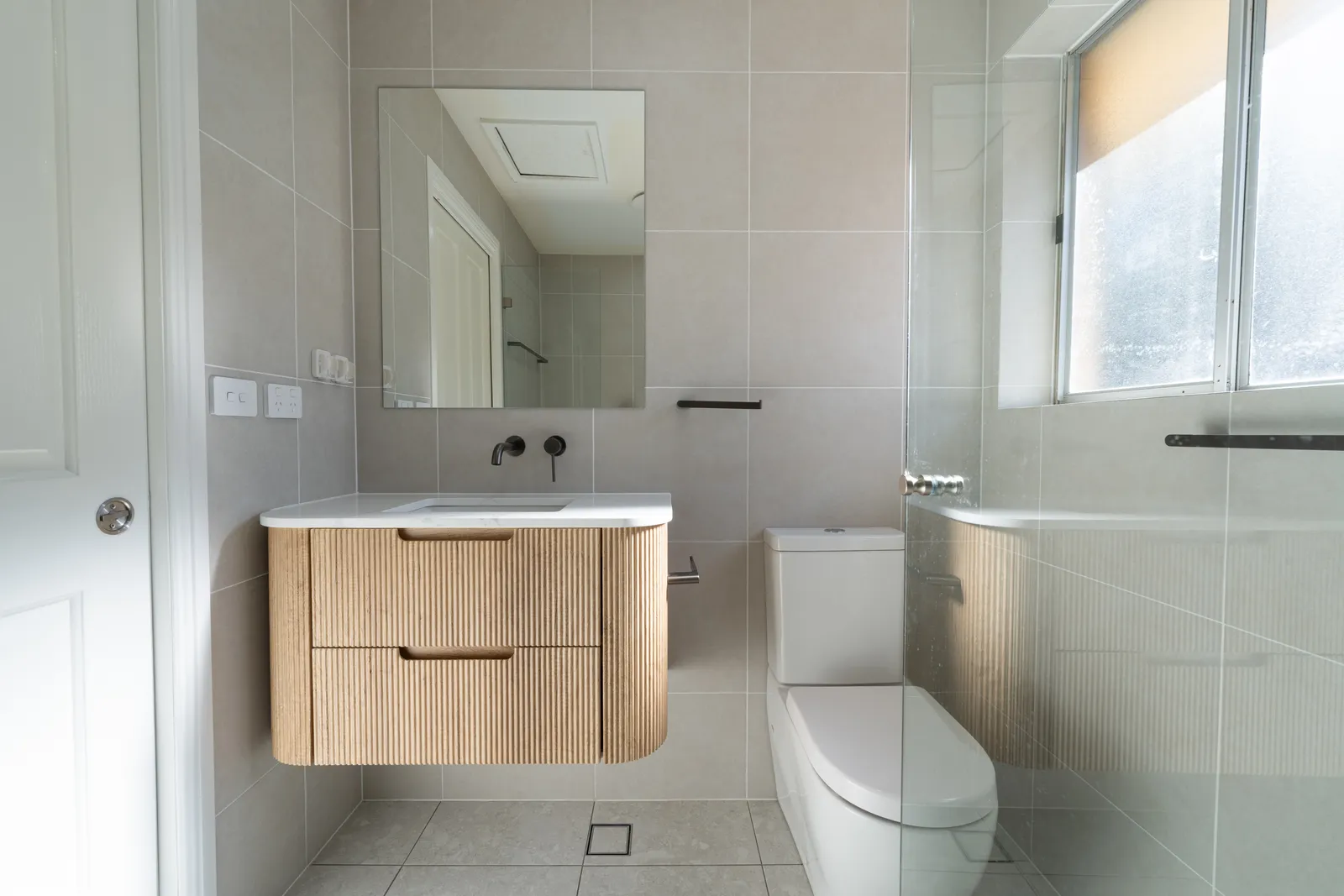 Toongabbie bathroom with fluted vanity, stone top and matt black wall-mounted tapware
