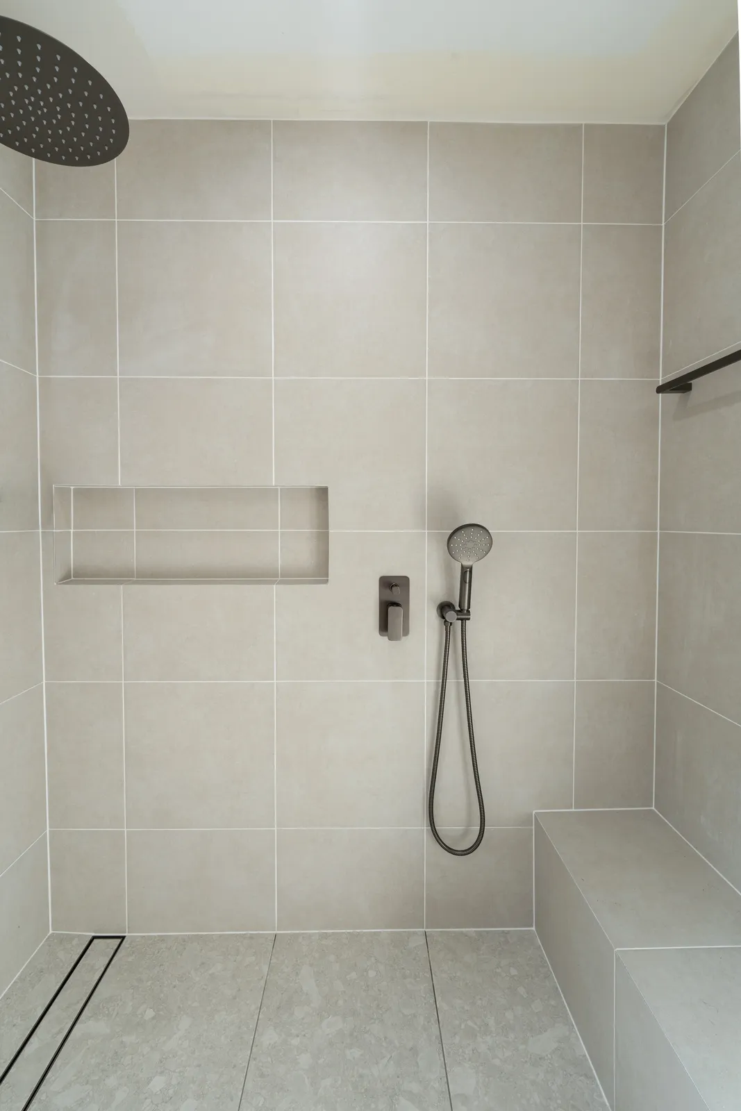 Shower recess with tiled niche, rail shower and bench seat in large-format tiles