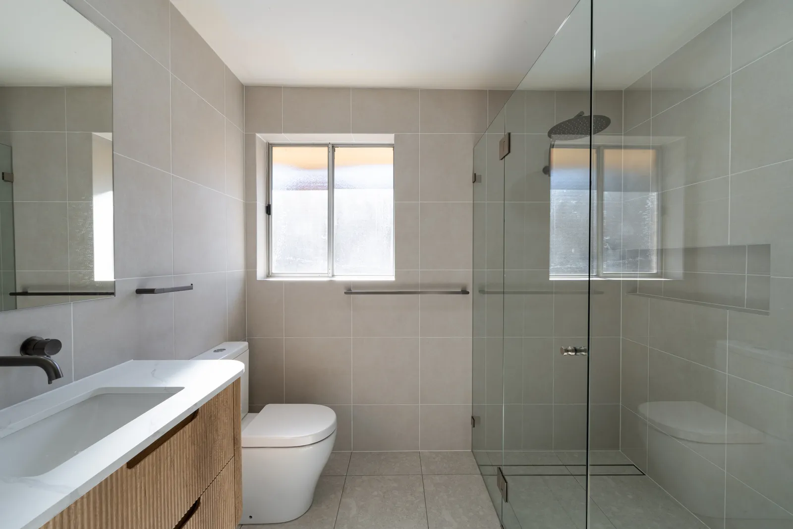Bathroom with large-format tiling, frameless glass shower screen and mirrored cabinet