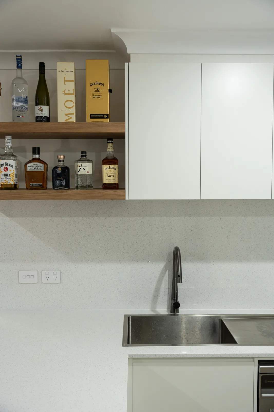 Kitchen sink run with gunmetal pull-down tapware, stone splashback and timber floating shelves