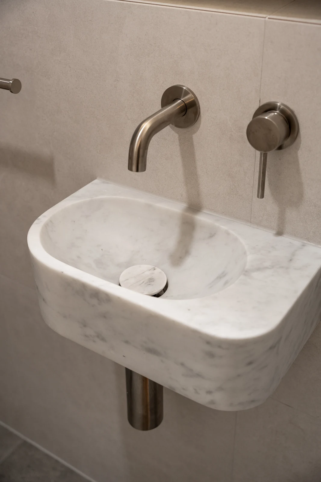 Close-up of the wall-hung Carrara marble basin and brushed nickel tapware in the powder room